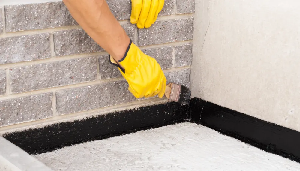 worker applying bitumen to waterproof